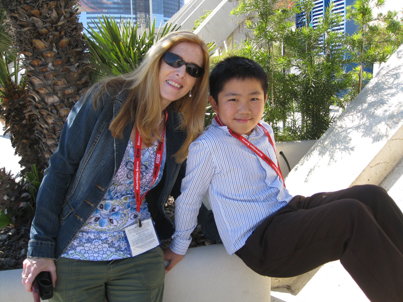 Liz H. Kelly and Perry Chen leaning on a wall by a palm tree